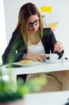 Pretty Young Woman Reading A Book And Having Breakfast At Home Stock Photo