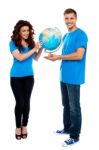 Smiling Young Couple Holding Globe Stock Photo