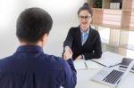 Businesswomen Shaking Hands Over A Desk As They Close A Deal Or Stock Photo