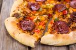 Delicious Baked Salami Pizza Served On Rustic Wooden Table Stock Photo