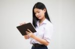 Portrait Of Thai High School Student Uniform Beautiful Girl Using Her Tablet Stock Photo