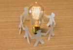 Paper Cut Of People Standing In A Circle Around Bulb Of Idea Stock Photo