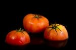 Three Red Tomatoes On A Black Background Stock Photo