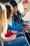 Students Having Fun With Smartphones And Tablets After Class Stock Photo