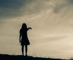 Silhouette Of Woman Praying Over Beautiful Sky Background Stock Photo