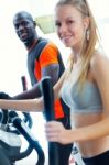 Young People With Elliptic Machine In The Gym Stock Photo