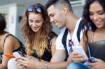 A Group Of Students Having Fun With Smartphones After Class Stock Photo