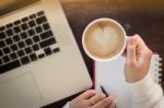 Hand On Cup Of Coffee At Work Table Stock Photo