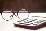 Calculator With Eyeglasses On Wooden Table Stock Photo