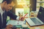 Business Man Sitting On A Calculator To Figure Out In A Coffee S Stock Photo