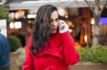 Woman In Red Coat Speak On Mobile Phone Stock Photo