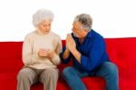 Elderly Couple Sitting In Sofa Stock Photo