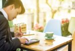 Business Man Sitting On A Calculator To Figure Out In A Coffee S Stock Photo