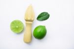 Fresh Limes And Wooden Juicer On White Background. Top View Stock Photo