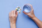 Taking Pill With Hand Holding Glass Of Water Stock Photo