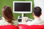 Rear View Of Young Couple Watching Tv On Sofa Stock Photo