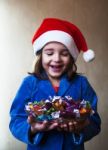 Girl In A Christmas Cap Holds A Dish With Chocolates Stock Photo