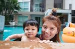 The Kid And Mom Play Together In The Pool Stock Photo