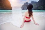 Young Woman In Red Bikini Sitting On The Beach Stock Photo