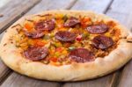 Delicious Baked Salami Pizza Served On Rustic Wooden Table Stock Photo