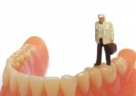 Miniature Elderly Standing On Removable Denture, On White Background. Dental Health Concept Stock Photo