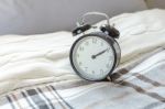 Modern Black Alarm Clock On Bed In Bedroom Stock Photo