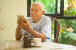 Happy Asian Senior Man Using The Mobile Phone In Home Stock Photo