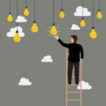 Businessman On The Ladder Catching A Light Bulb Idea Stock Photo