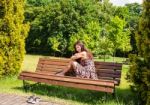 Young Girl Sitting On A Park Bench Stock Photo