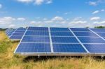 Field With Rows Of Blue Solar Collectors In Grass Stock Photo