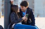 Young Couple Of Tourist In Town Using Mobile Phone Stock Photo