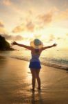 Happy Girl On The Beach At Sunrise Stock Photo