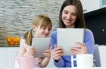 Mother And Daughter Using A Digital Tablet In Kitchen Stock Photo