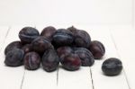 Tasty Purple Plums Isolated On A White Wooden Background Stock Photo