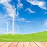 Wind Turbine On Green Grass Field And Blue Sky Background Stock Photo