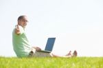 A Young Men Sit On The In The Park Using A Laptop Stock Photo