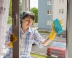 Young Smiling Woman Washes A Window Stock Photo