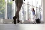 Woman With Luggage Waving To Boyfriend At Airport Stock Photo