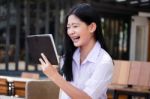 Portrait Of Thai High School Student Uniform Beautiful Girl Using Her Tablet Stock Photo