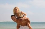 Couple Piggyback Ride At Beach Stock Photo