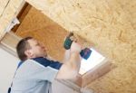 Man Worker Twists The Screw Into The Ceiling With A Screwdriver Stock Photo