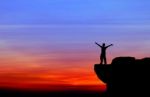 Silhouette Of A Man On The Rock At Sunset Stock Photo