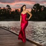 Beautiful Young Woman In The Gardens Wearing A Long Silk Red Dress Stock Photo