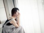 Sad Woman Sitting Alone In Room Stock Photo