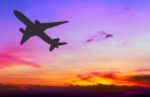 Silhouetted Commercial Airplane Flying At Sunset Stock Photo