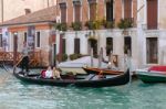 Gondolier Ferrying Passengers Along A Canal In Venice Stock Photo