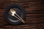 Black Empty Plate Fork Spoon On Wooden Table Background Stock Photo