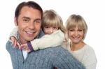 Fun Loving Family Of Three, Girl Piggybacking Her Father Stock Photo