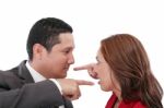 Young Couple Pointing At Each Other Against A White Background Stock Photo