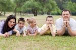 Cheerful Family Of Five Lying On Lawn Stock Photo